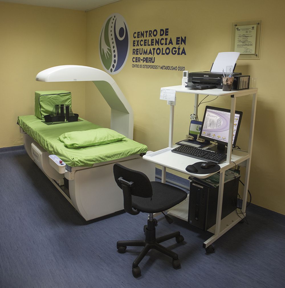 Una habitación con una cama y un escritorio con un cartel que dice centro de excelencia en reumatología.
