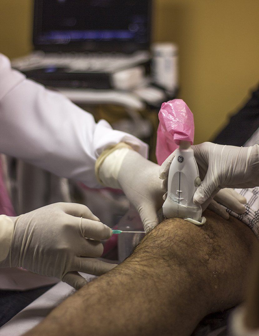 Unas manos de médico con bata blanca y guantes de latex practicando una ecografía de rodilla