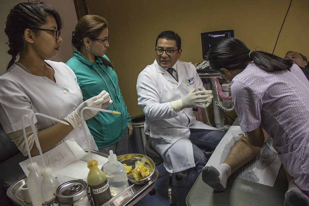 Un grupo de médicos y enfermeras están trabajando con un paciente en una habitación de hospital.