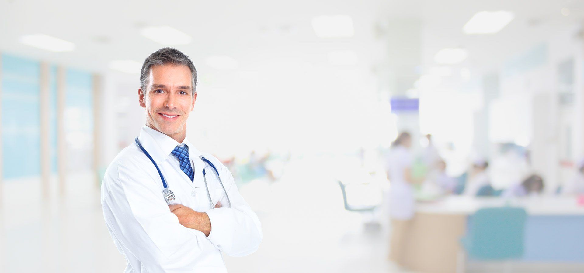 Un médico está de pie en un hospital con los brazos cruzados y sonriendo.