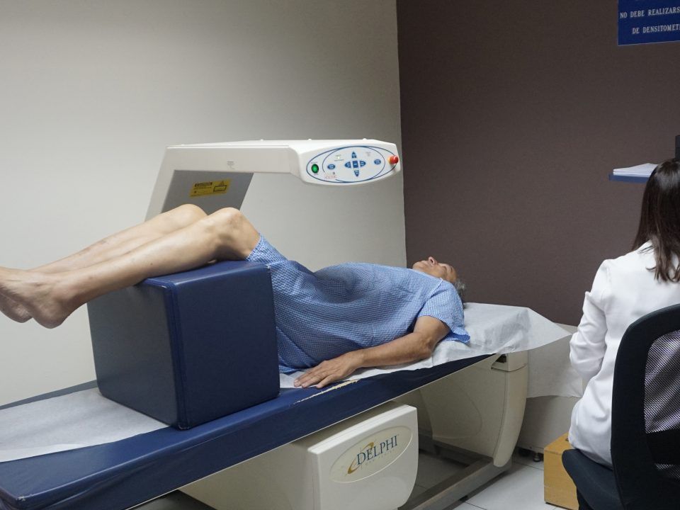 Un hombre está acostado en una cama con las piernas cruzadas mientras un médico lo observa.