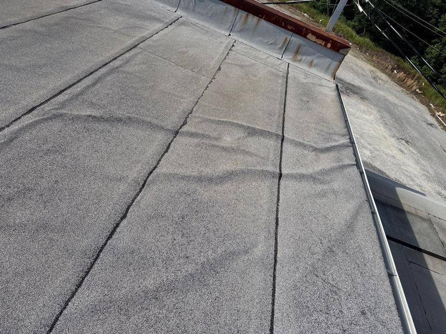Empty concrete rooftop with seams and a gravel edge under daylight