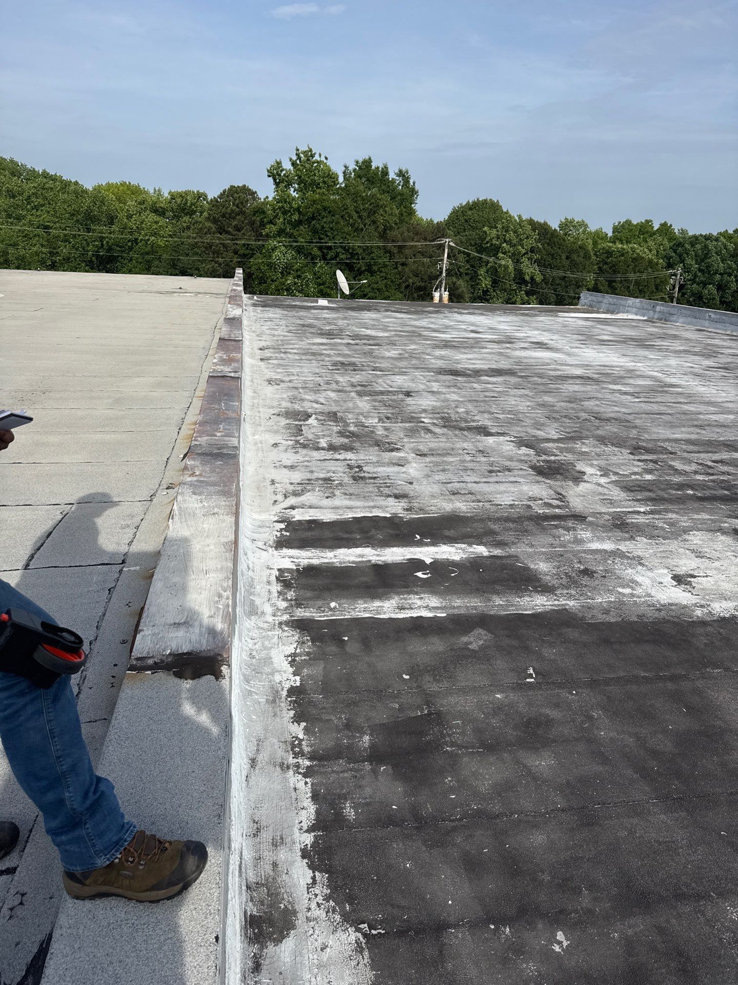 Flat rooftop with a person standing at the left edge and trees in the background