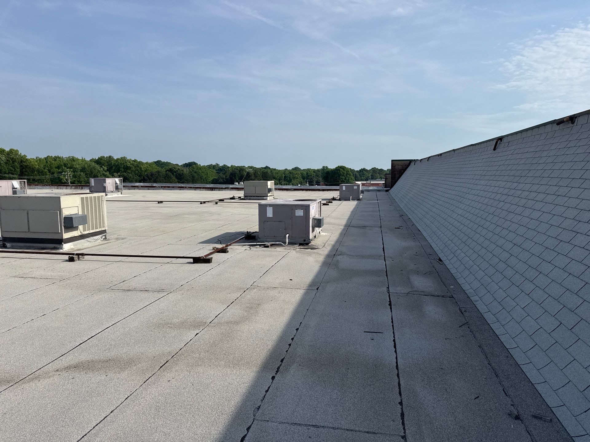 A person is standing on top of a roof with a hole in it.