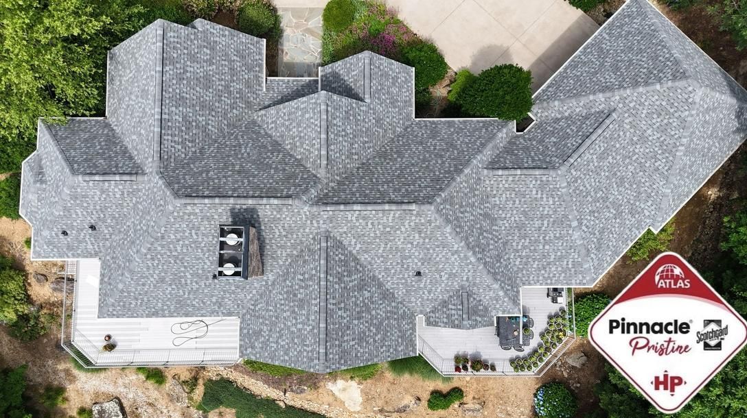 Aerial view of a gray-shingled house with a white garage and a small Pinnacle sign in the yard.