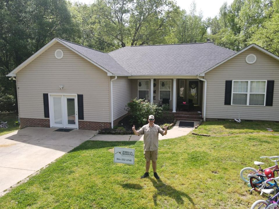 A man is standing in front of a house holding a sign.