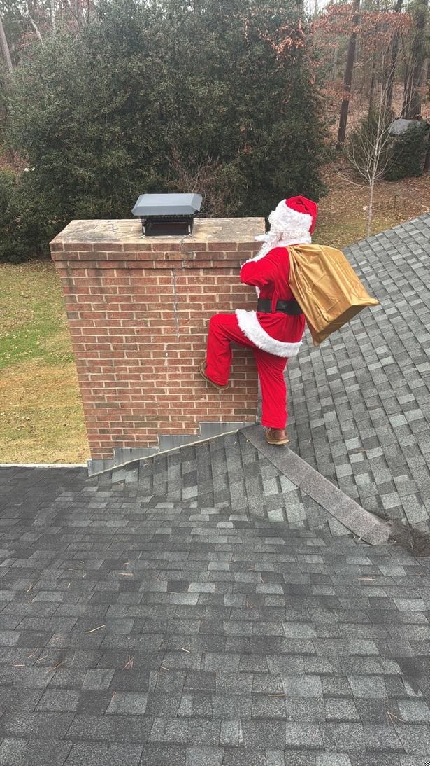 Santa climbing a roof with a gold sack beside a brick chimney