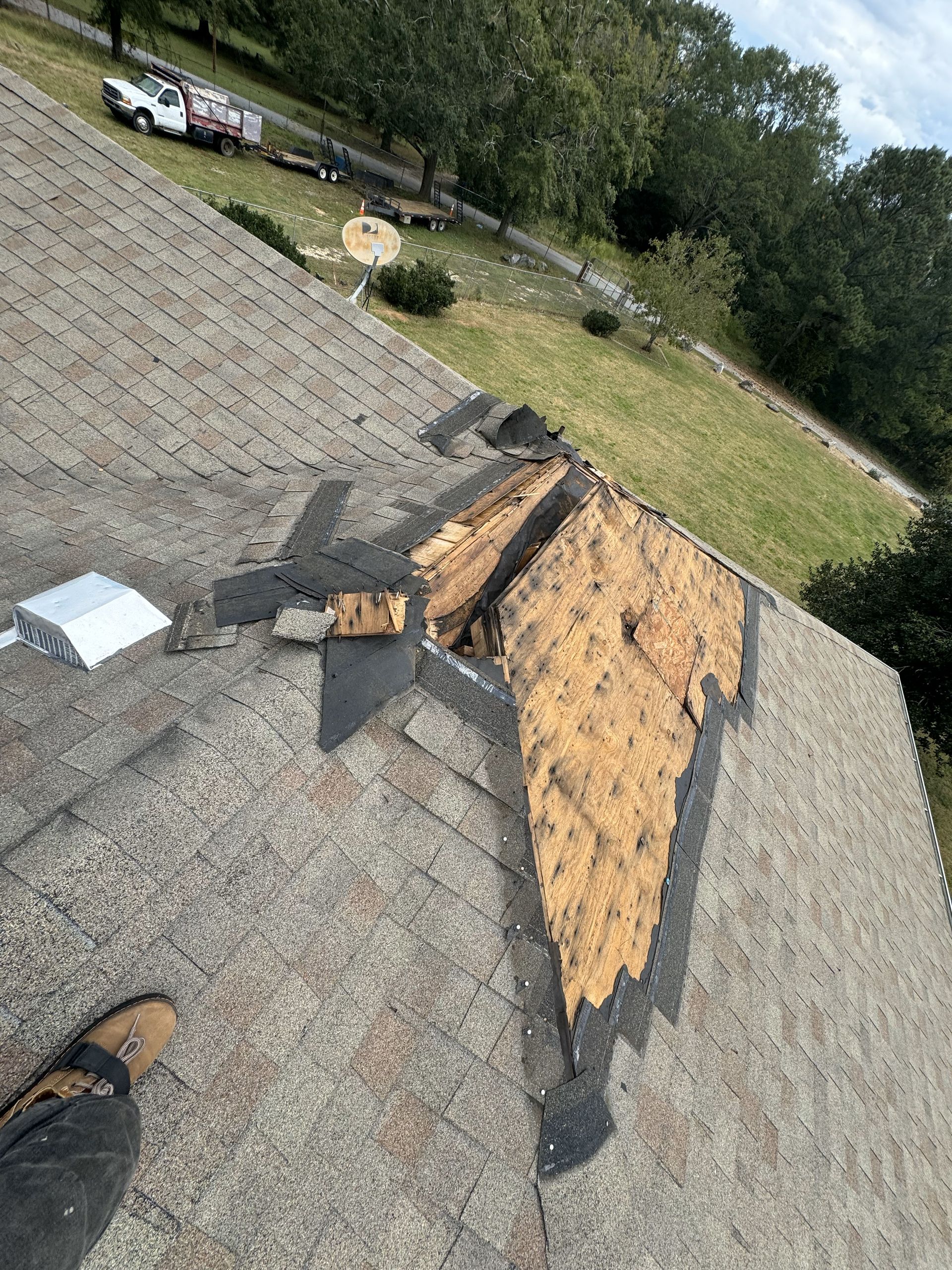 A person is standing on top of a roof with a hole in it.