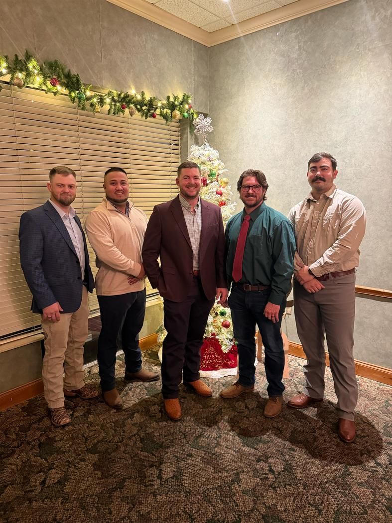 Five people posing in a decorated indoor room with holiday garland and a lit Christmas tree