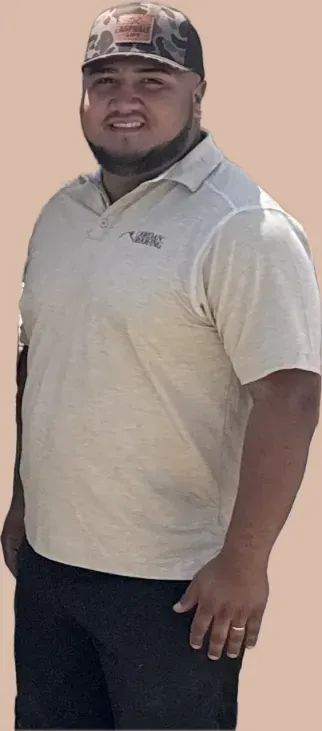 A man wearing a hat and a white shirt is standing in front of a white background.