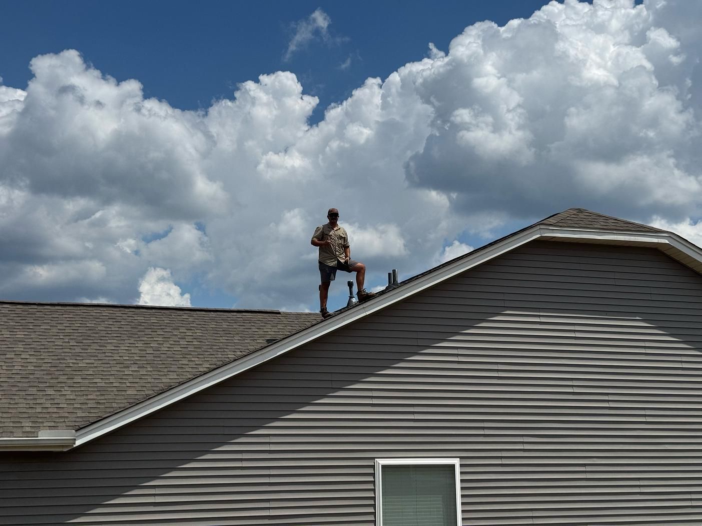 A person is standing on top of a roof with a hole in it.