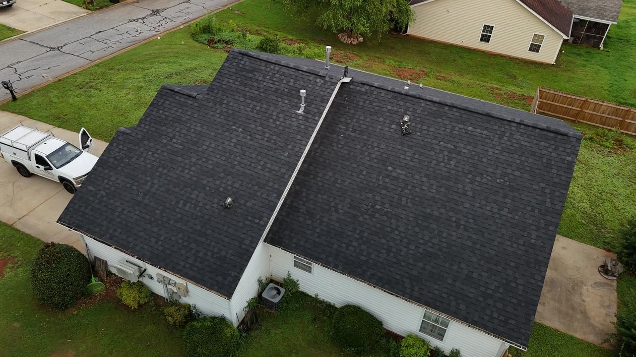 Aerial view of a dark gray roof on a suburban house with a driveway and green lawn