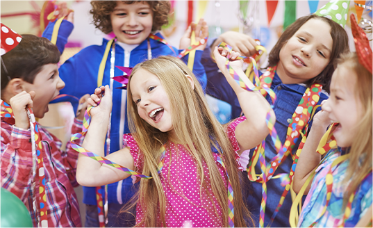 A group of children are playing with streamers at a birthday party.