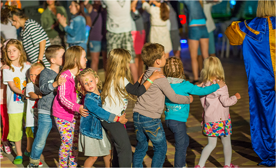A group of children are dancing with a clown in a blue cape Glen Waverly