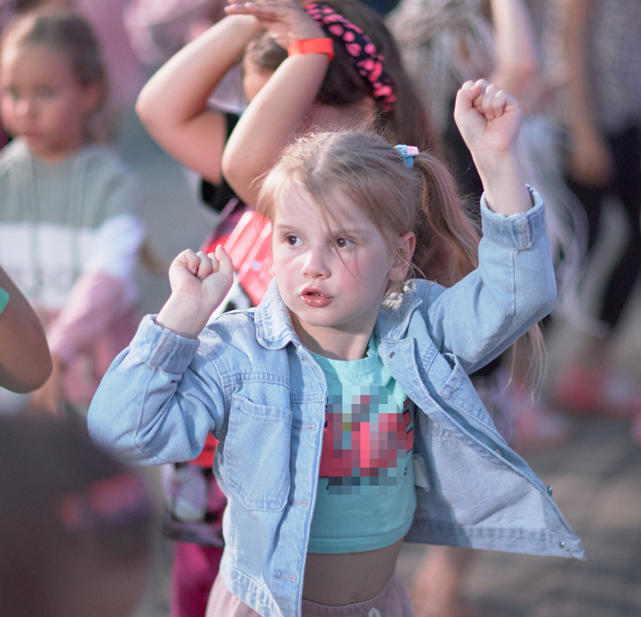 A little girl in a blue denim jacket is dancing