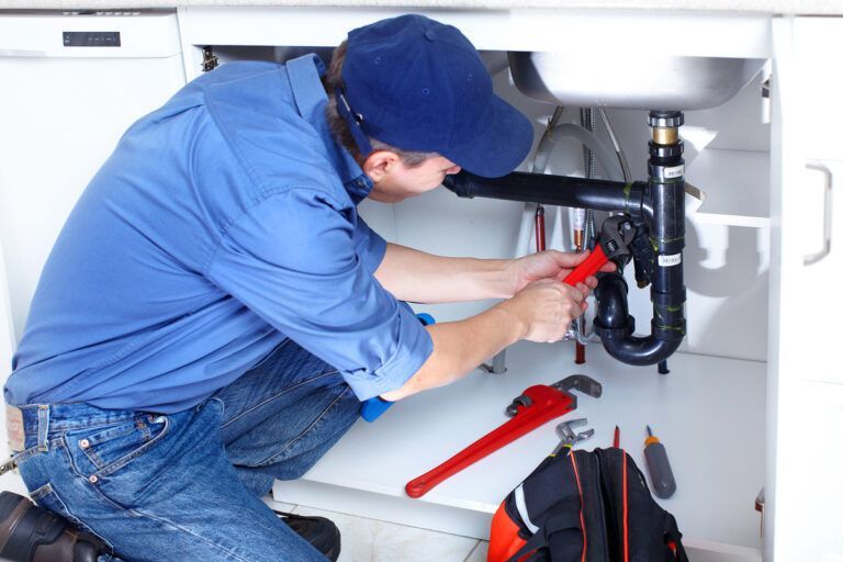 plumber fixing pipes under a sink