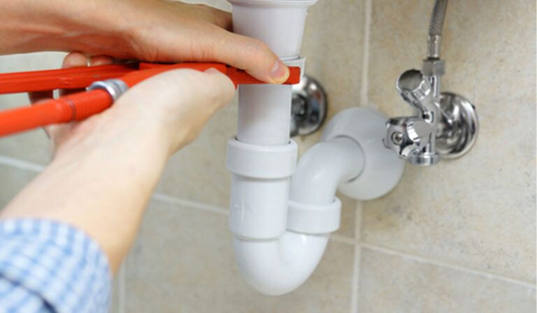 plumber fixing a pipe under a sink