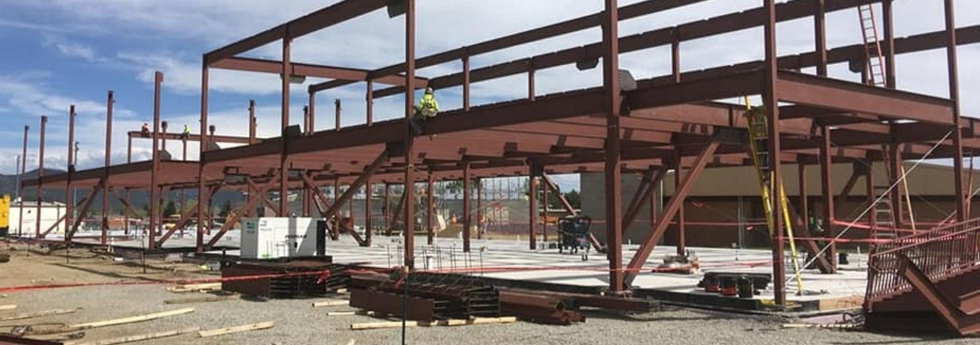 Steel framework of a building under construction with workers and equipment on site