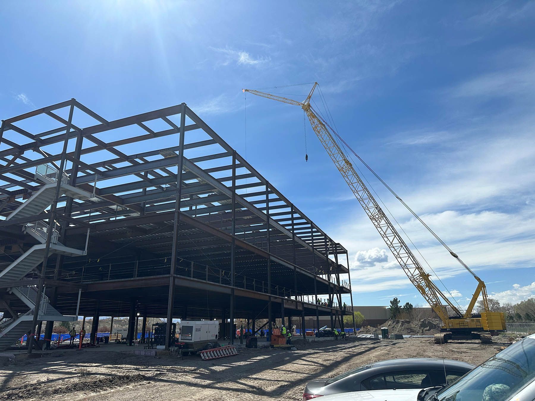 Steel frame building under construction with a yellow crane on a sunny site
