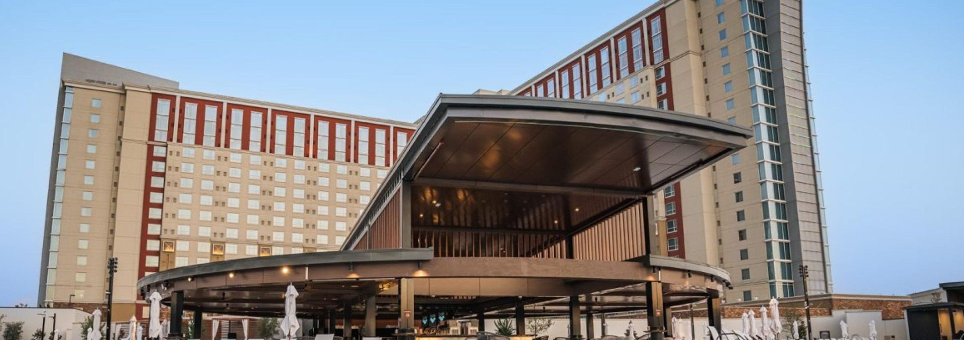 Modern hotel or office building entrance with a large canopy and tall curved towers behind it