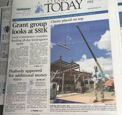 Newspaper front page with a crane lifting steel at a construction site under blue sky
