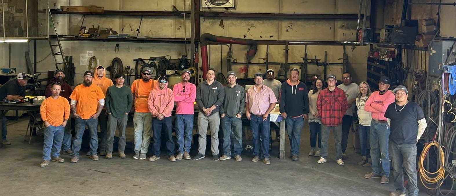 Group of workers in bright shirts standing together inside an industrial warehouse