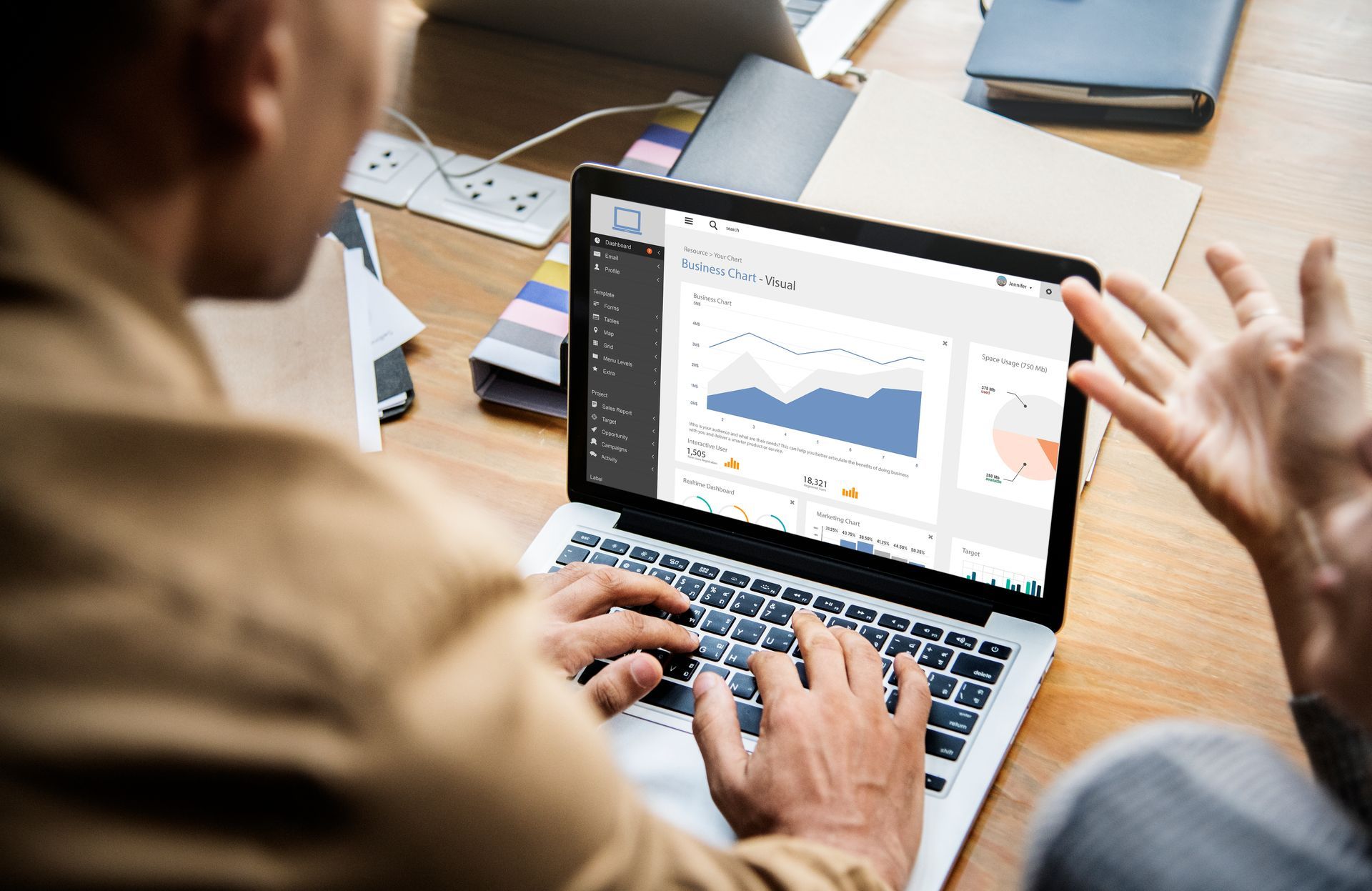 Two people looking at laptop screen with business graphs, discussing data.