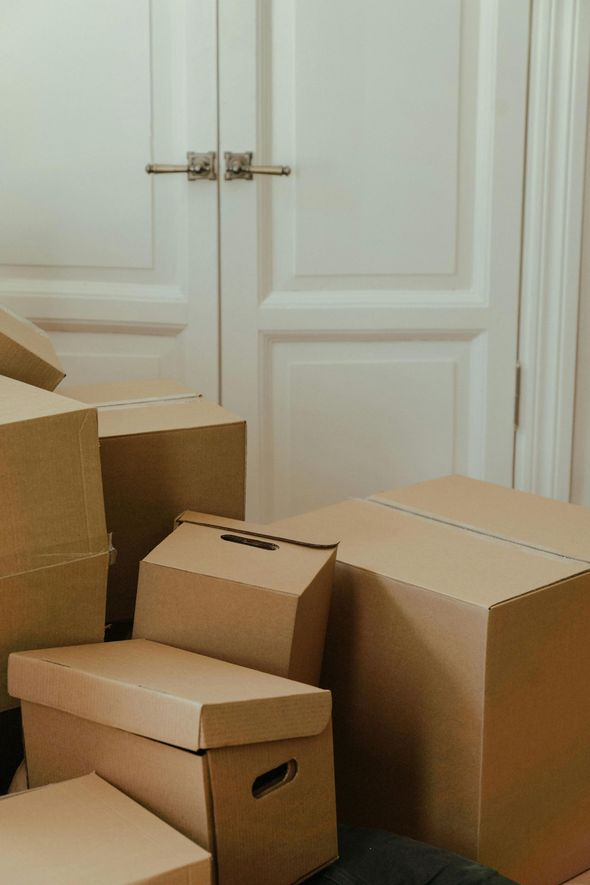 Cardboard moving boxes stacked near a white closed door.