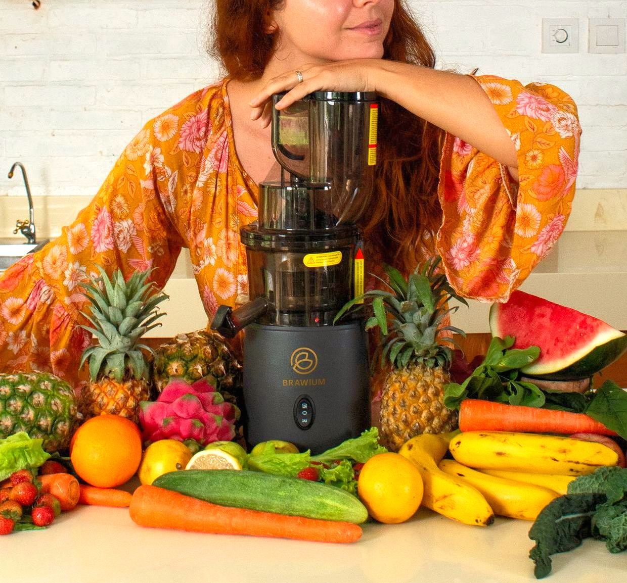 Wanita dengan juicer yang dikelilingi buah dan sayuran.