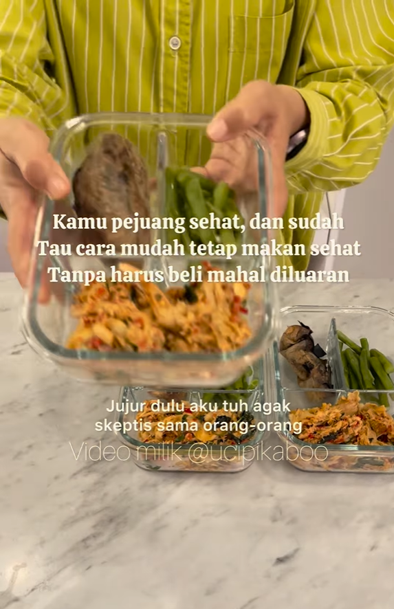 Seseorang memegang wadah kaca berisi makanan sehat. Hamparan teks: