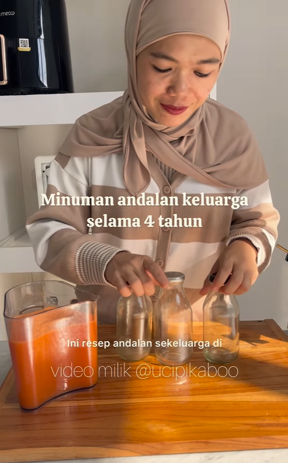 Wanita berhijab menuangkan minuman ke dalam botol, meja kayu, hamparan teks: