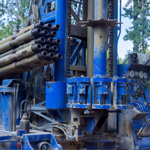 Blue drilling rig with stacked pipes at an outdoor industrial site