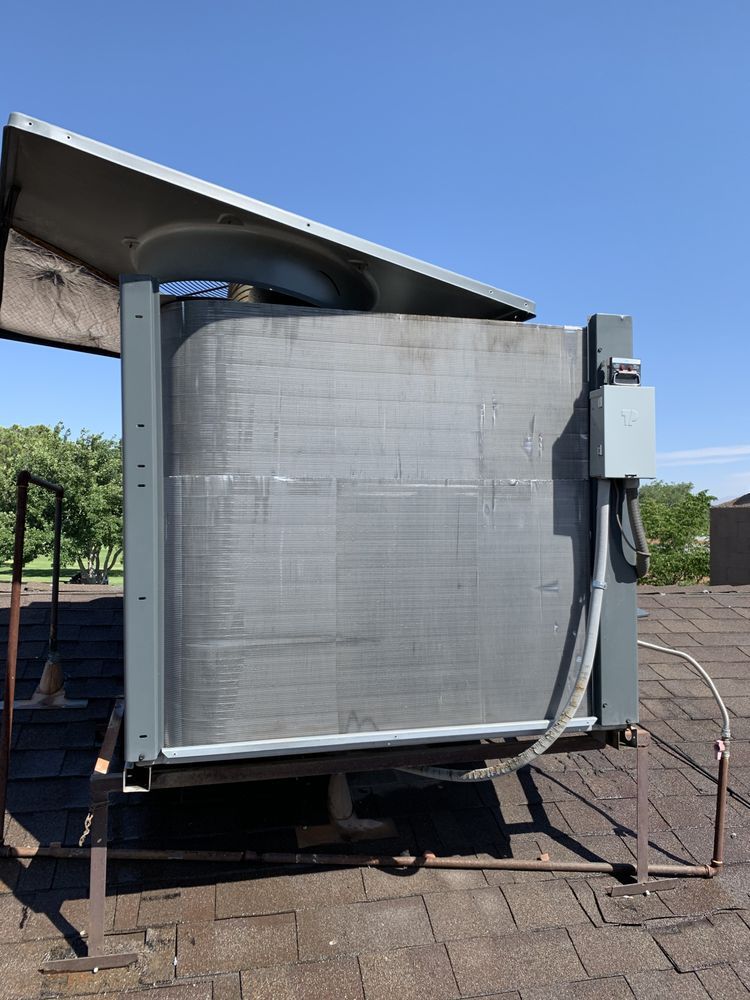 An industrial HVAC unit on a roof, featuring gray metal side panels, a top cover, and an electrical disconnect box.