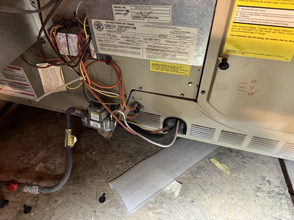 A furnace unit interior with wiring, a gas valve, and metal panels, seen in a utility space.