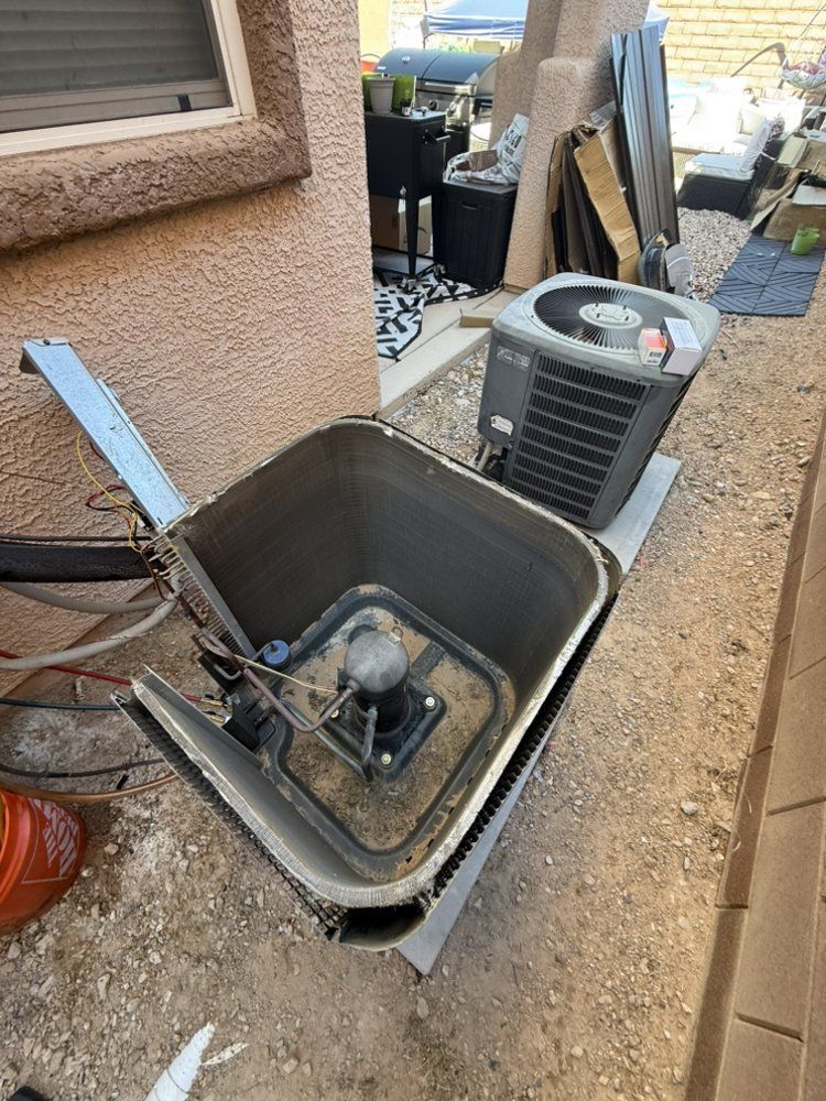 An outdoor view of an HVAC unit with its top panel removed, revealing the interior coil, next to an intact air conditioner.