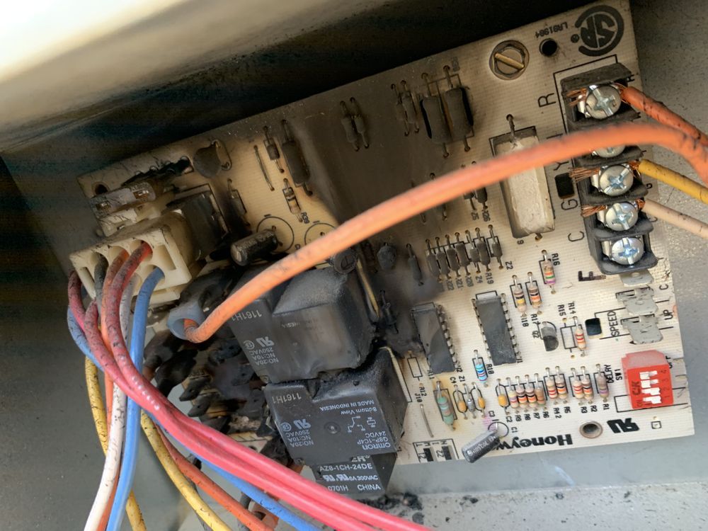 A damaged Honeywell control board for an HVAC system with visibly scorched electronic components and wiring.