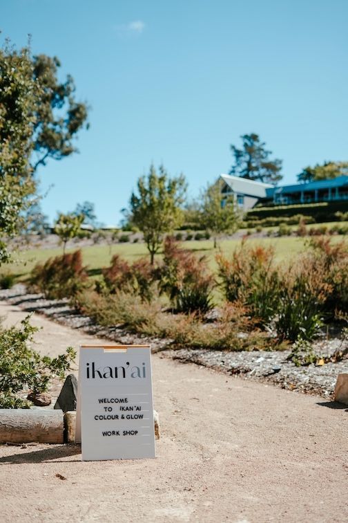 Arm with foundation swatches in various shades, next to a black tube, on green grass — Ikan'ai In Bowral, NSW