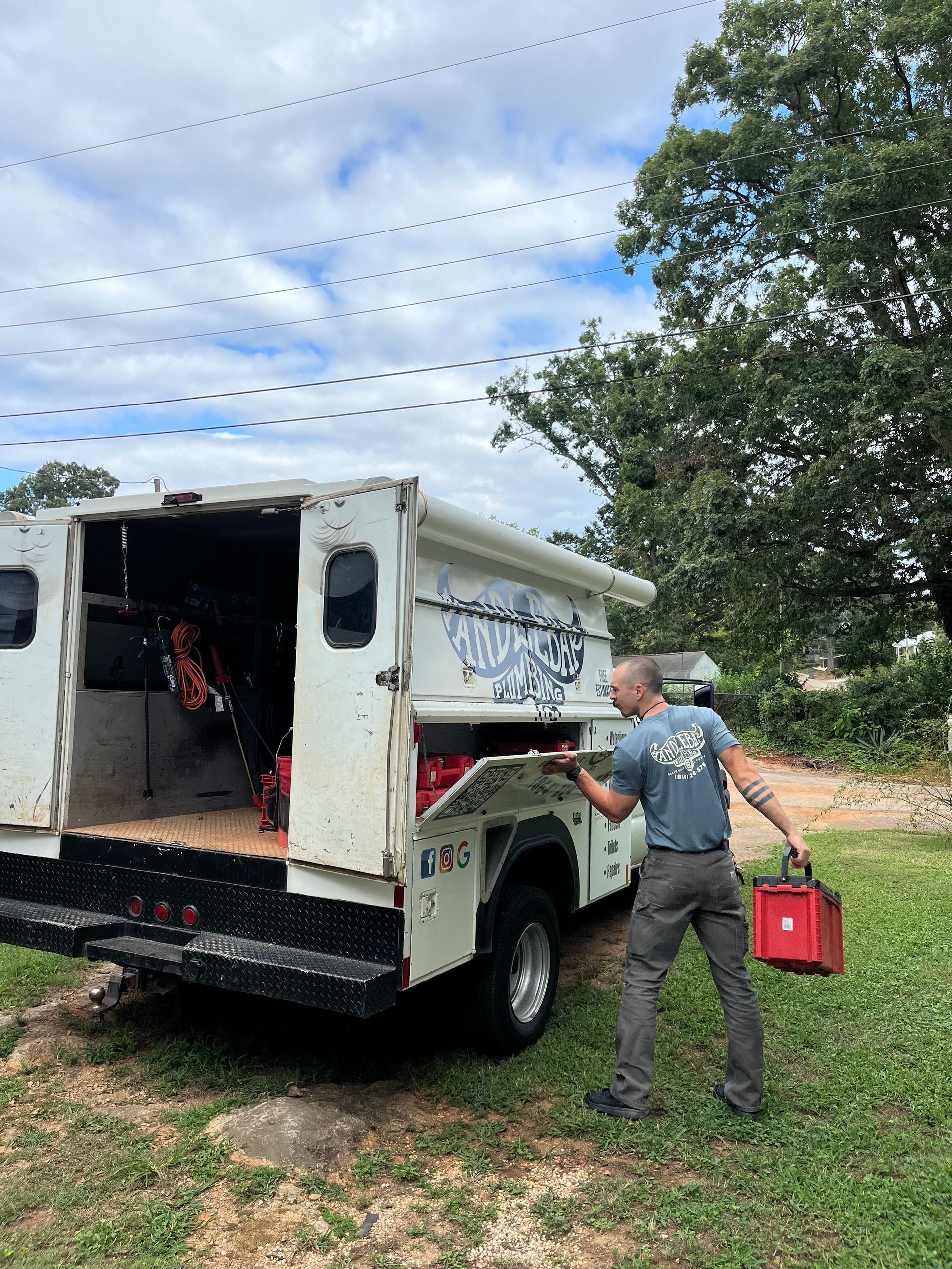 A person wearing gloves and glasses opens a red toolbox in a van filled with organized red toolboxes.