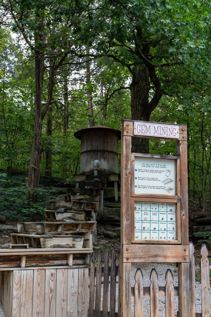 Three people examining artifacts at an outdoor wooden sluice in a park