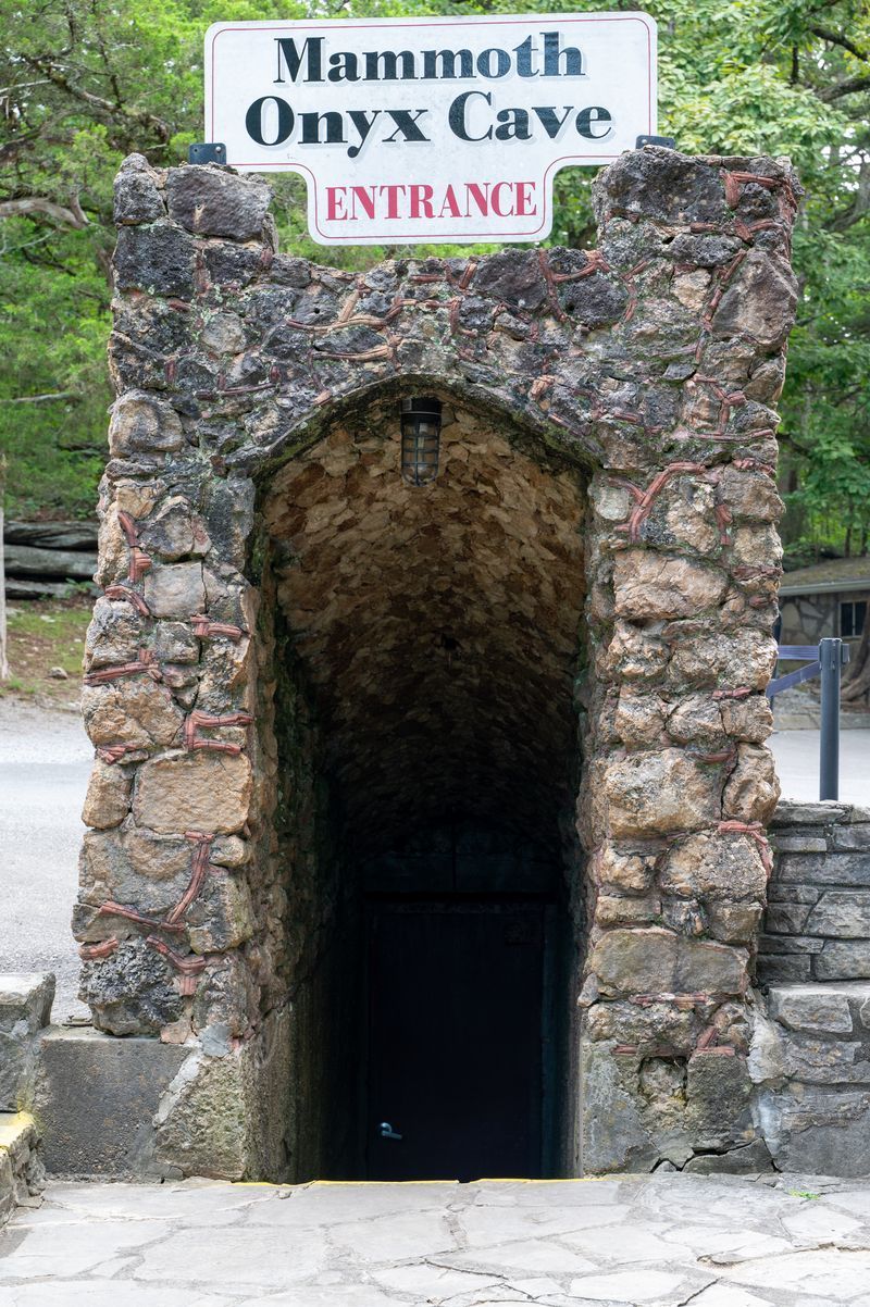 Dim cave with rocky walls and a shallow green-lit pool reflecting light.