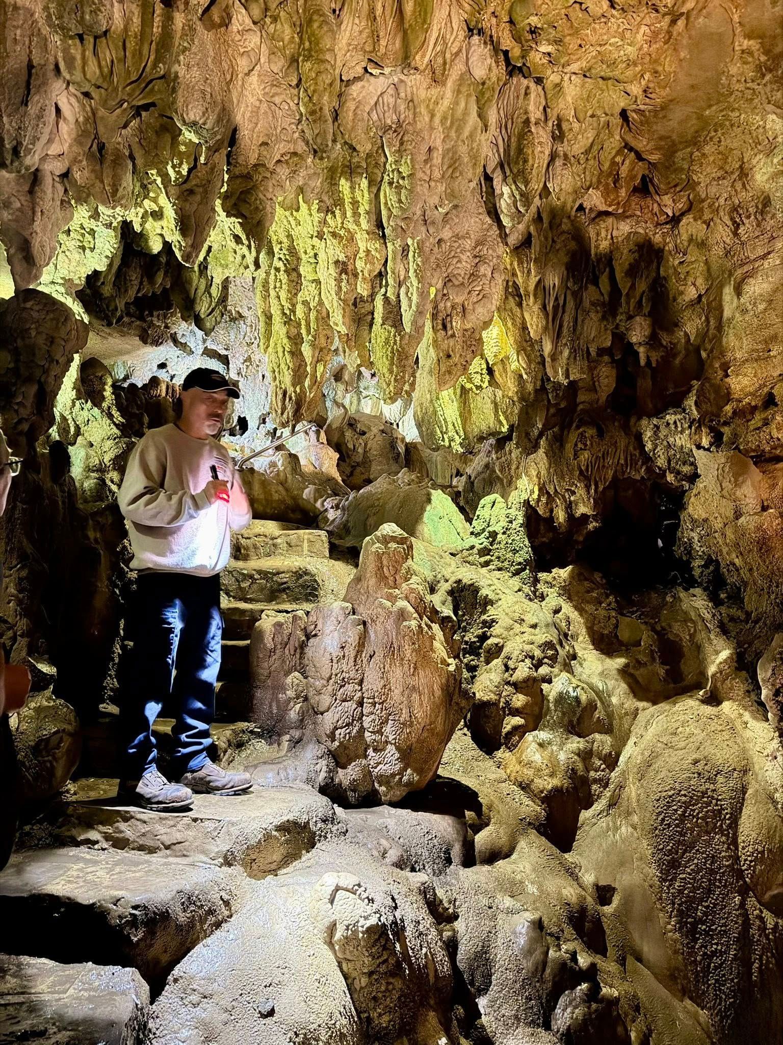Person standing on rocks inside a cave with a glowing, textured ceiling