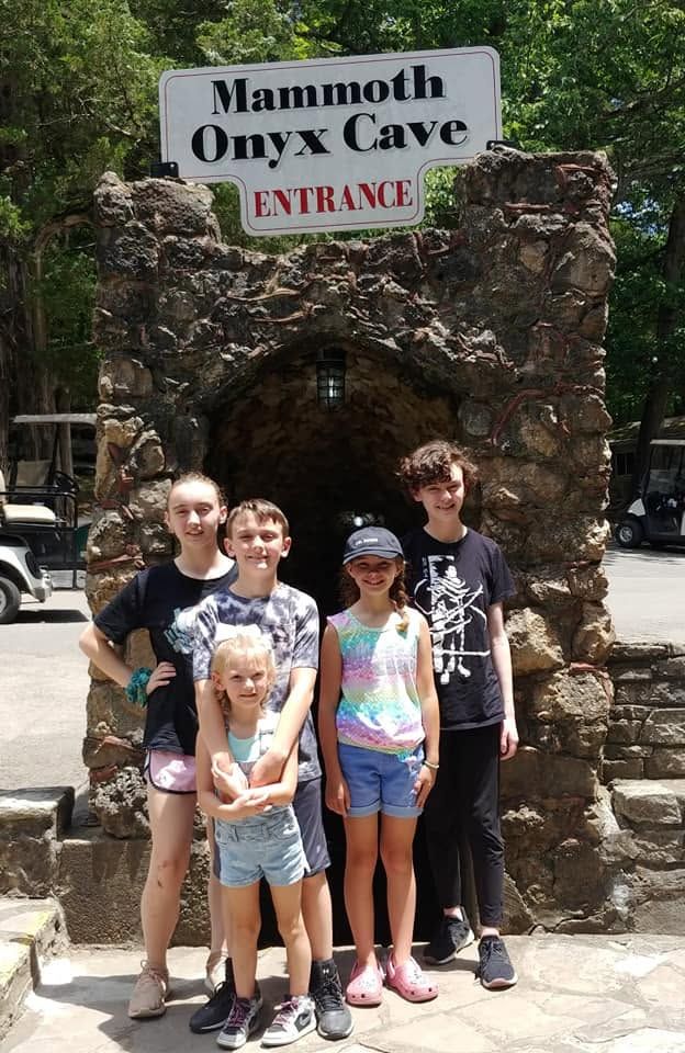 Group of people posing at the entrance sign for Mammoth Onyx Cave.