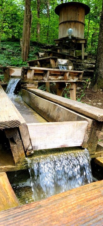 Wooden water mill with flowing stream in a lush green forest