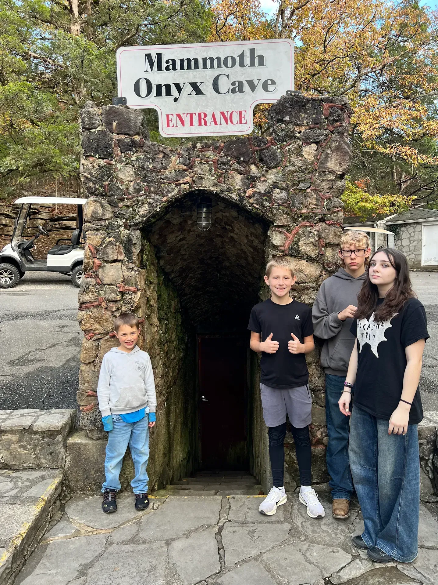 Four people standing at the entrance of Mammoth Onyx Cave under a sign reading “EVERYDAY.”