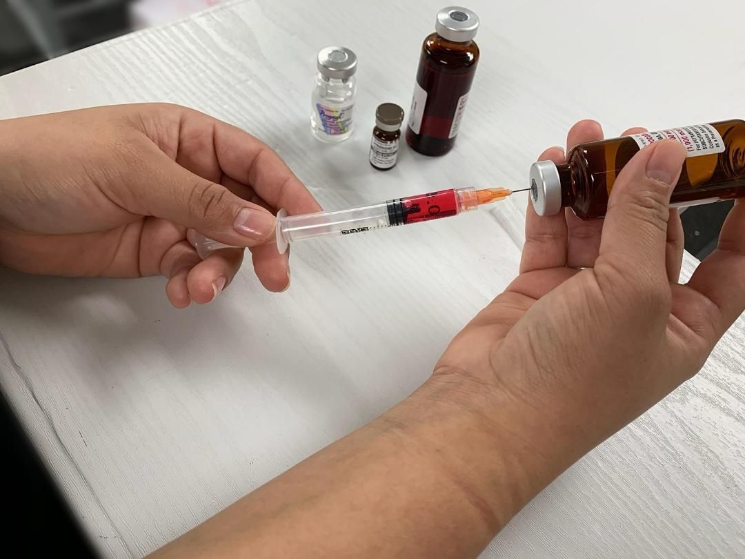A person is holding a syringe and a bottle of medicine.