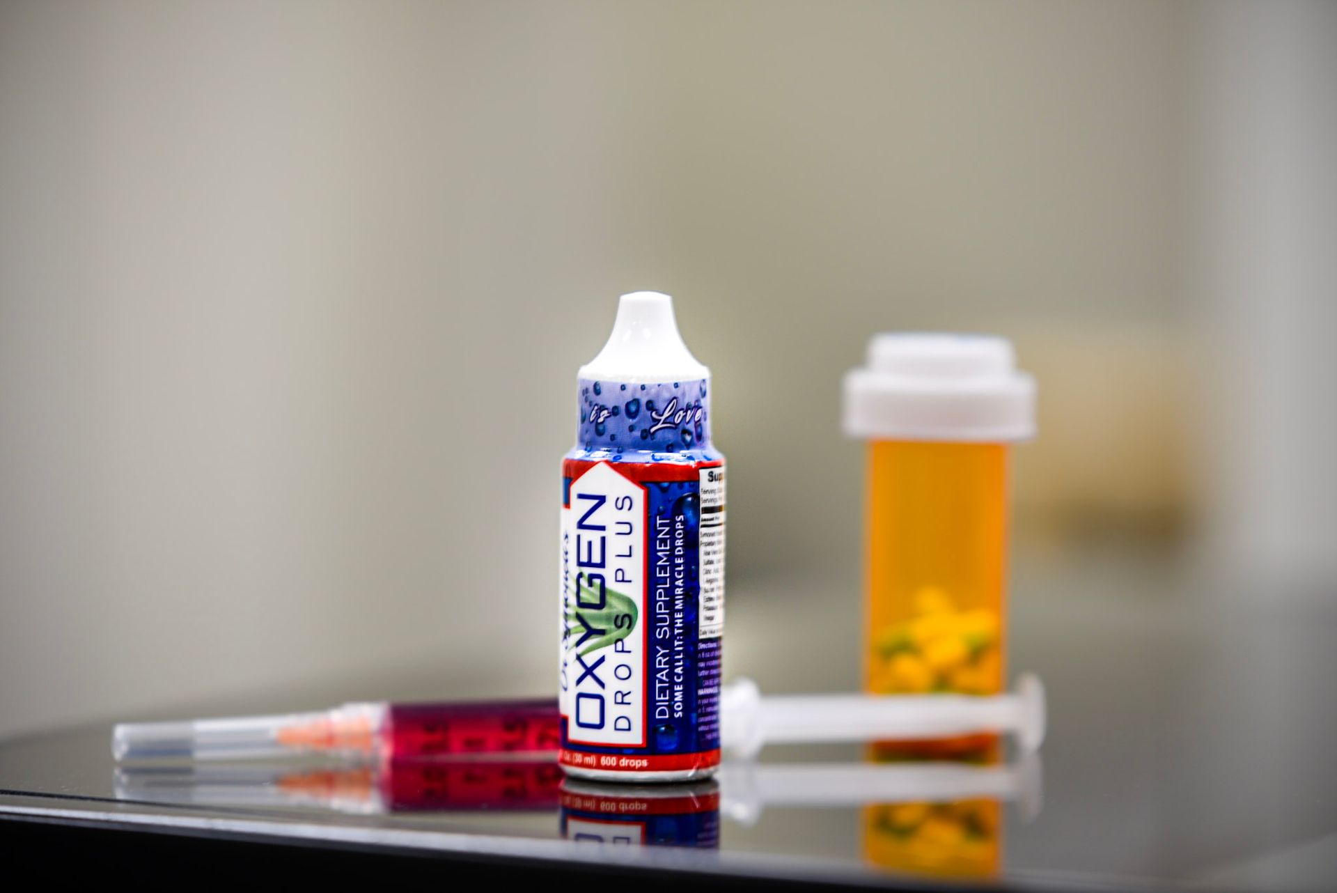 A bottle of oxygen drops plus next to a bottle of pills