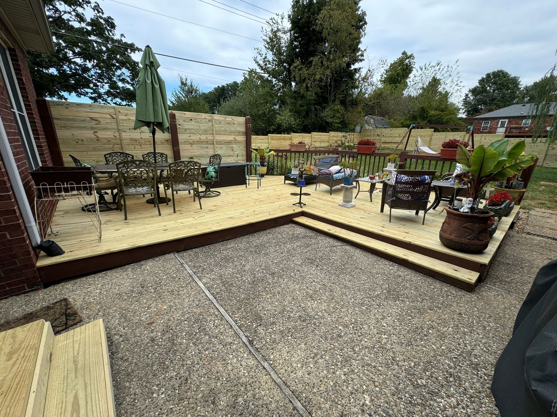 Outdoor patio with café tables, umbrellas, and potted plants on a gravel and wooden deck.