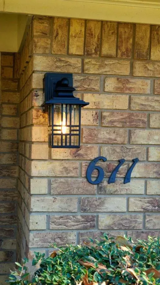 Brick wall with a black lamp and the address 