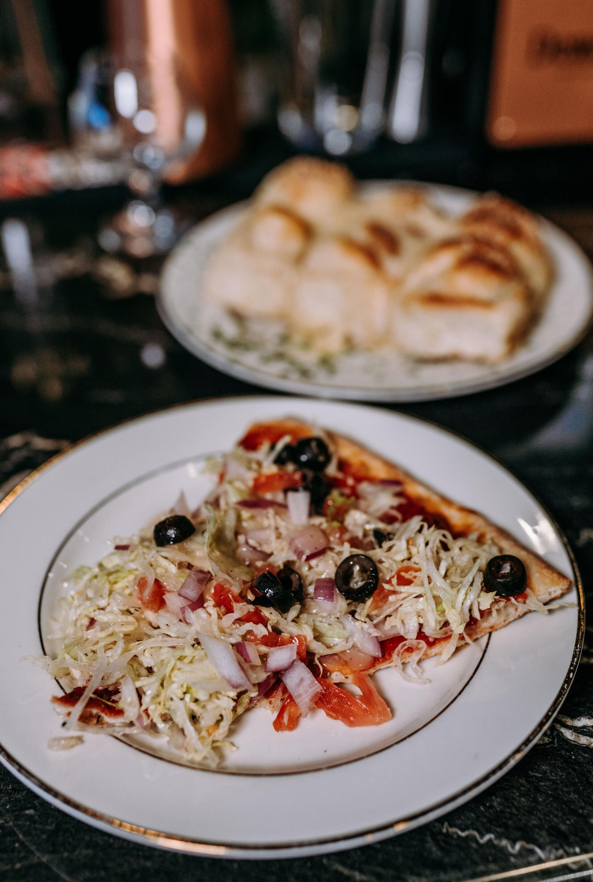 A slice of pizza is on a white plate on a table.