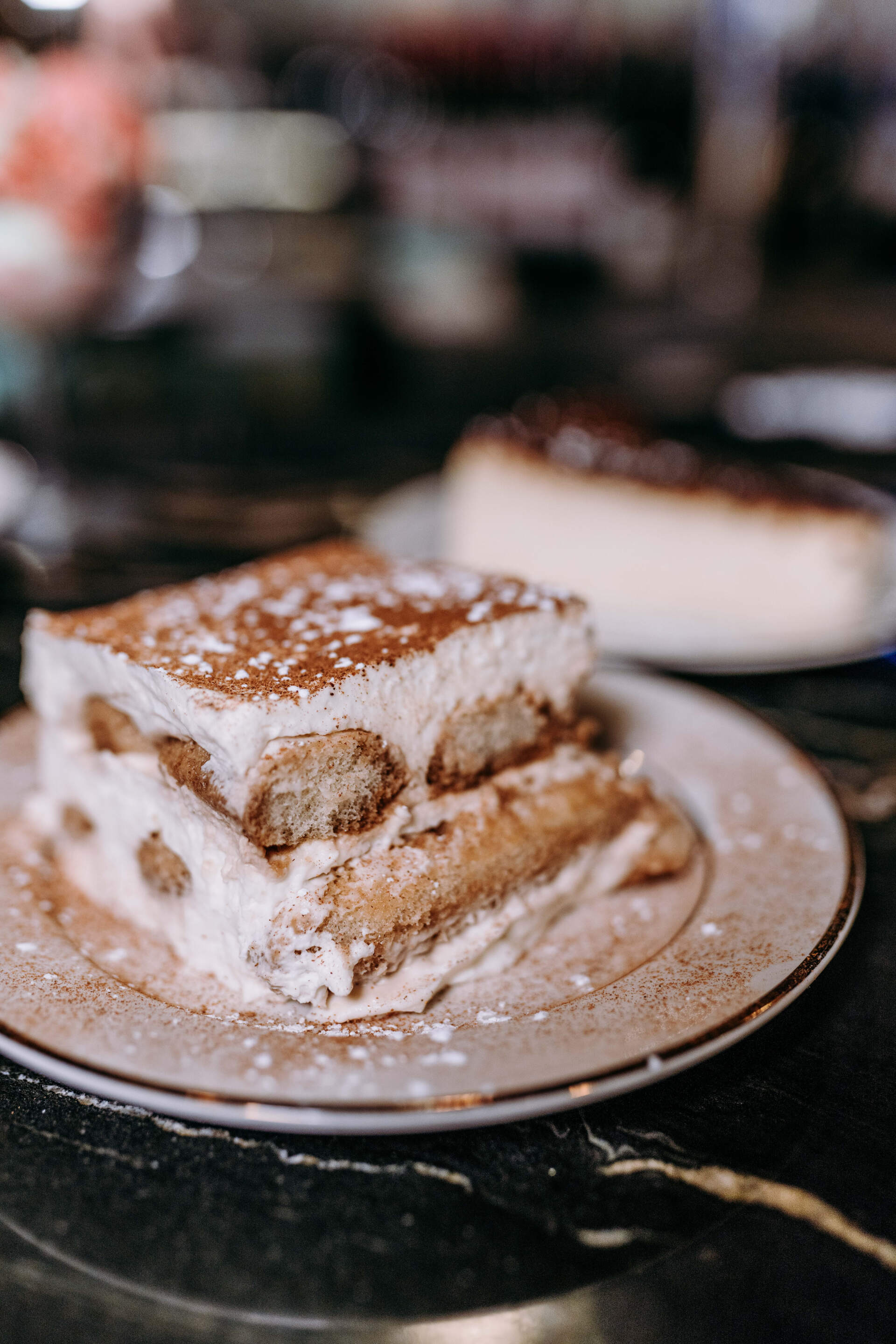A slice of tiramisu is on a plate on a table.